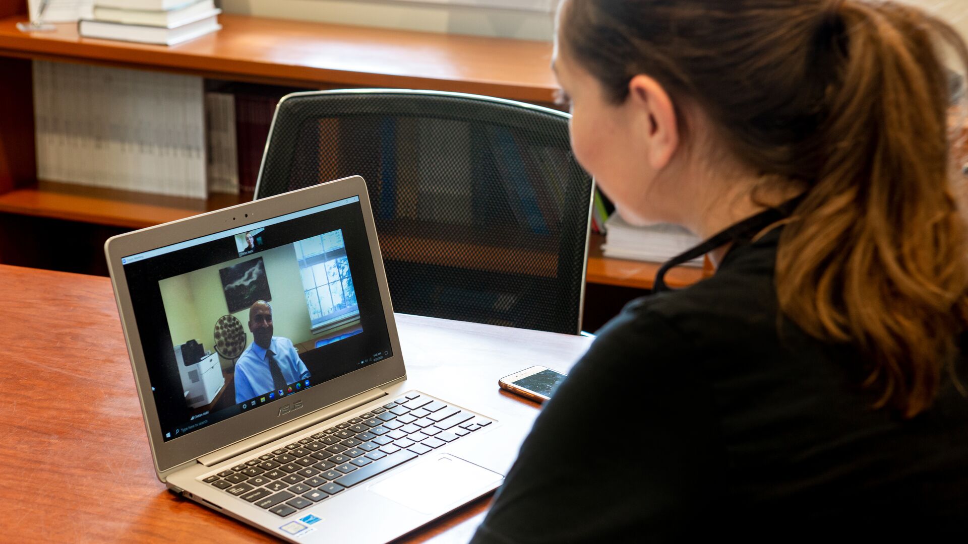 student sitting at desk with laptop on to a virtual call with a counselor