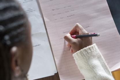 close up of student taking notes using a pencil and paper