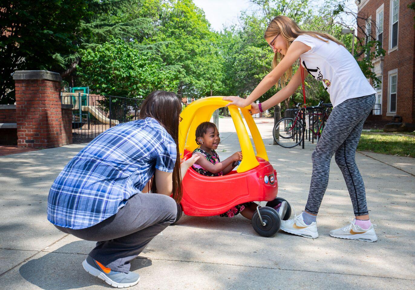 UMD students in speech-language pathology and audiology playing with a child in a toy car