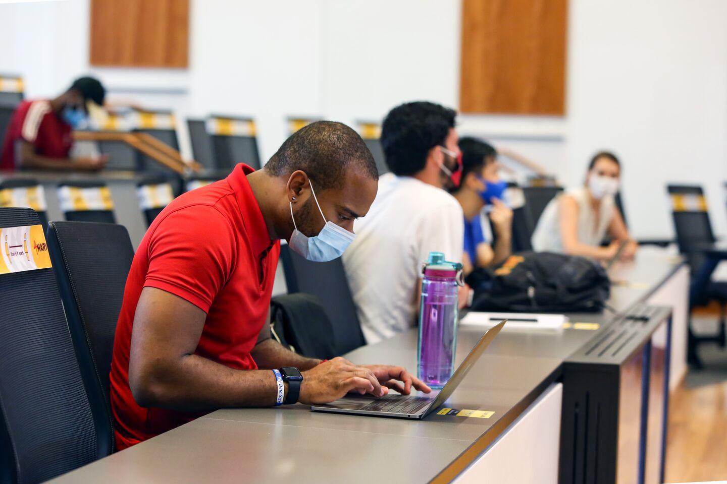 Students in a socially-distanced classroom wearing masks in Edward St. John Learning and Teaching Center.