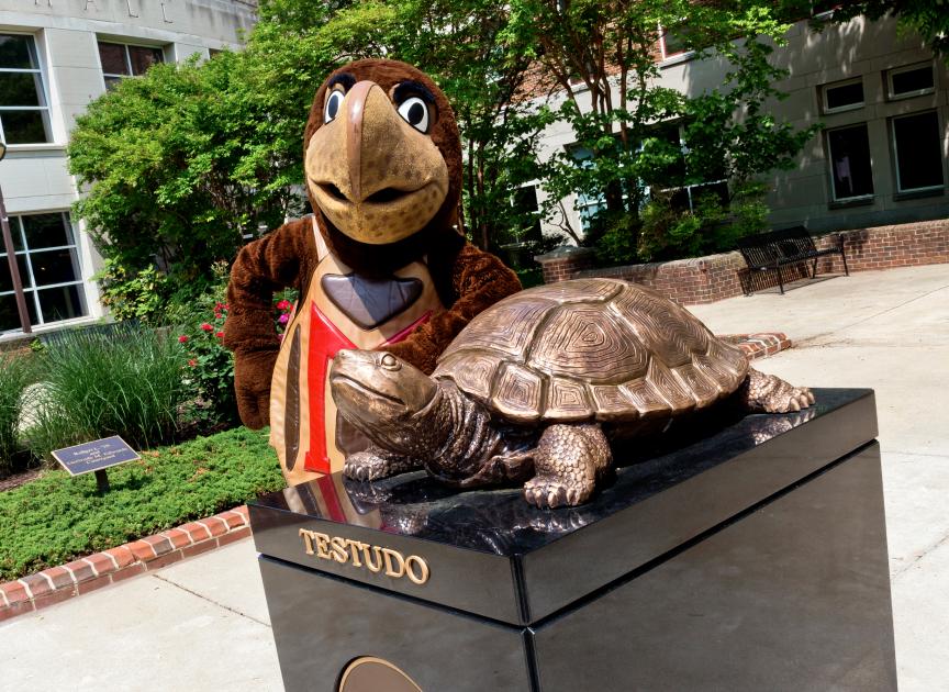 Testudo mascot with the bronze Testudo Statue in front of Van Munching Hall.