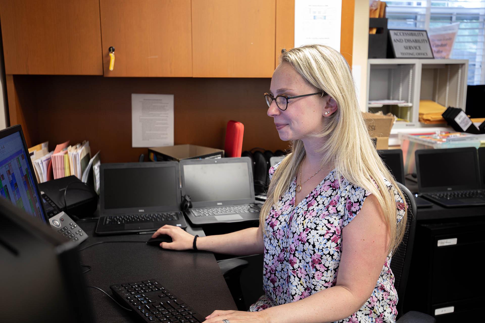 ADS staff member posing in front of her work station with two computer monitors in the background